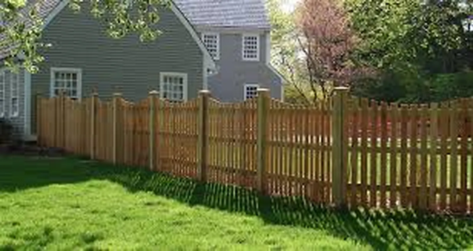 Wood shadowbox privacy fence with lattice top in a landscaped yard