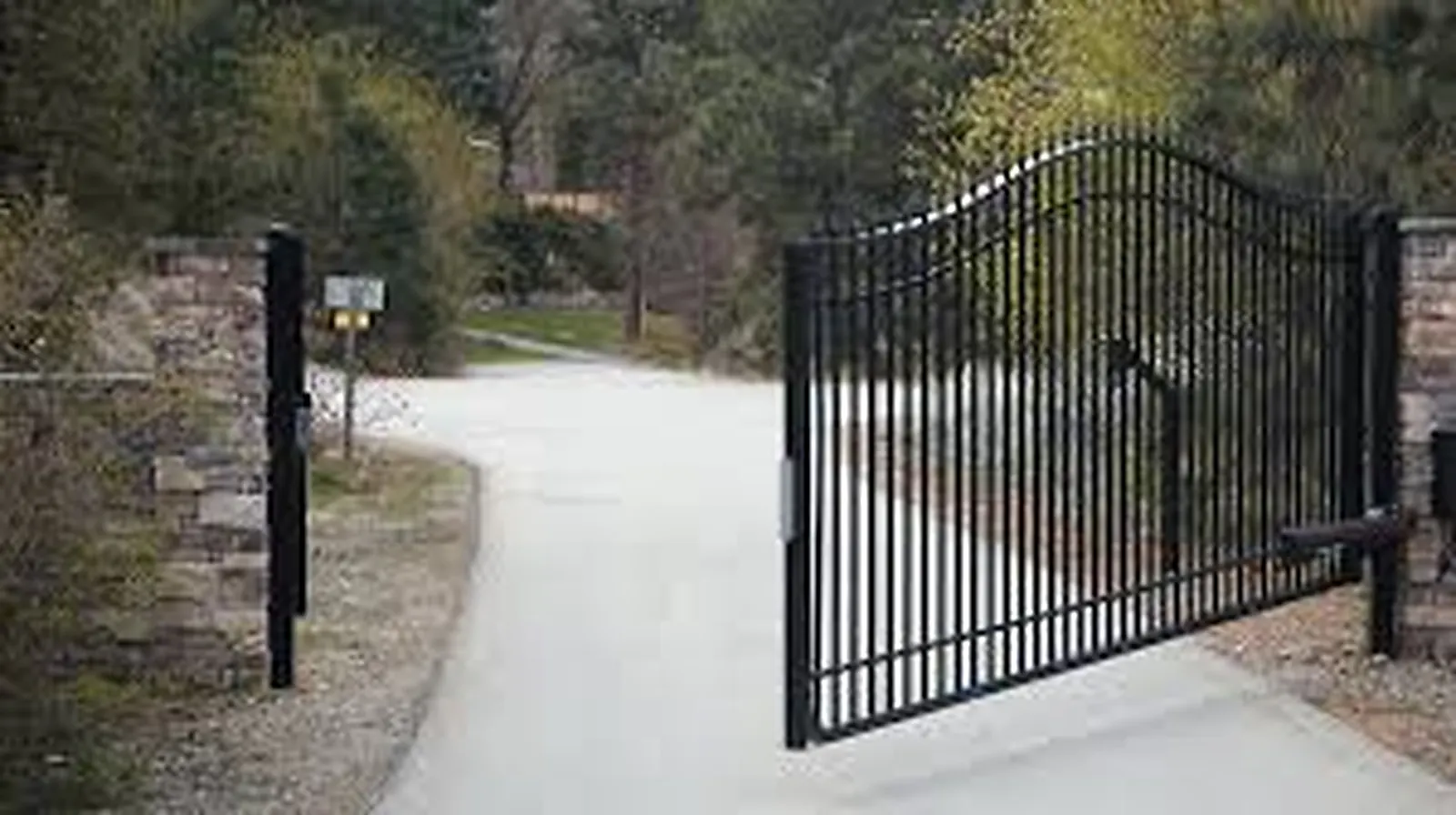 Automated electric driveway gate with stone pillars at a private estate