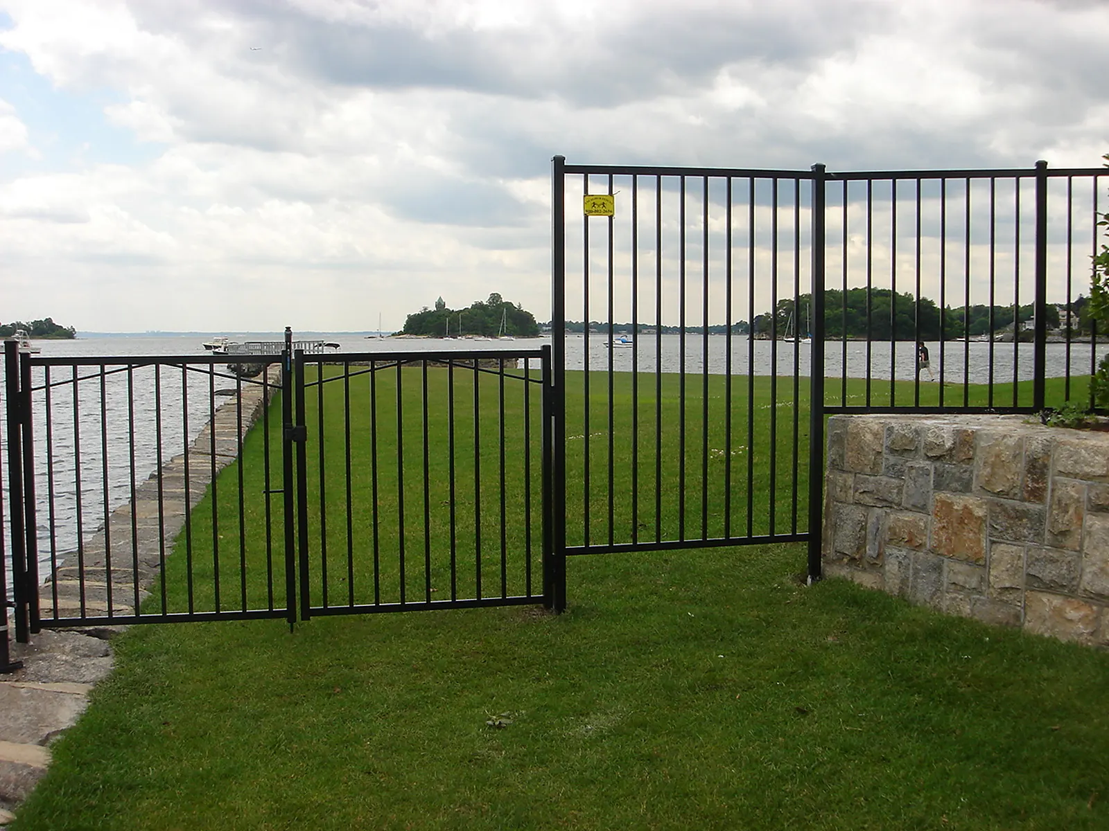 Ornamental wrought iron fence with spear-top pickets along a front yard